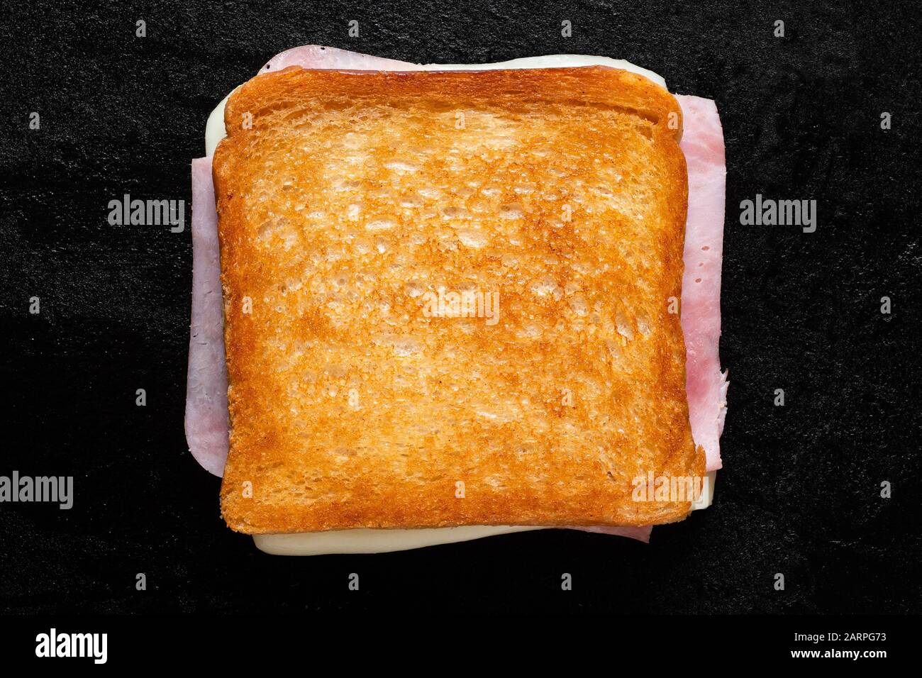 Sandwich grillé au fromage classique et au jambon isolé sur une grille en fonte noire. Vue de dessus. Banque D'Images