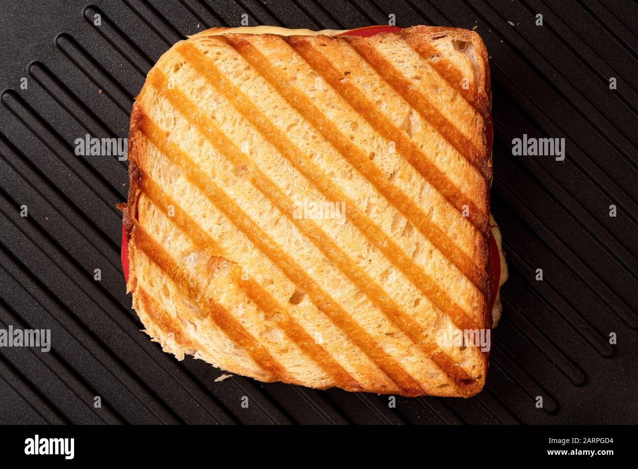 Sandwich au fromage grillé et à la tomate avec des marques de gril isolées sur le gril antiadhésif noir. Vue de dessus. Banque D'Images