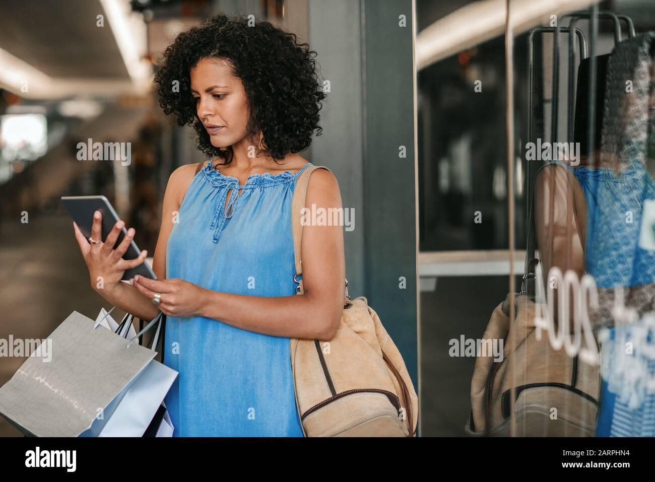 Jeune femme utilisant une tablette numérique tout en dehors des achats de vêtements Banque D'Images