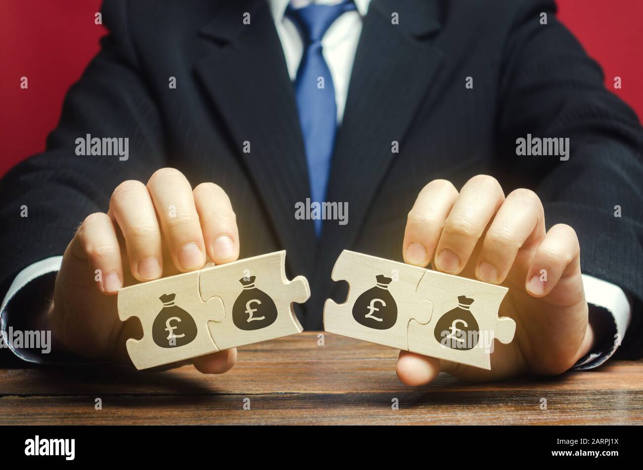 Businessman sépare le puzzle en bois avec une photo de l'argent. Le concept de la gestion financière et de la répartition des fonds. Épargner et investir. Banque D'Images