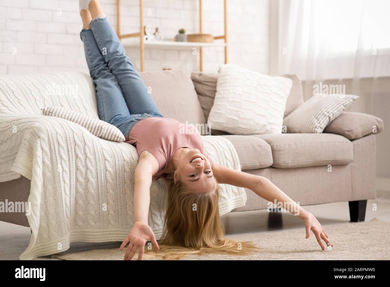 Jeune femme qui pose à l'envers sur le canapé à la maison Photo Stock -  Alamy