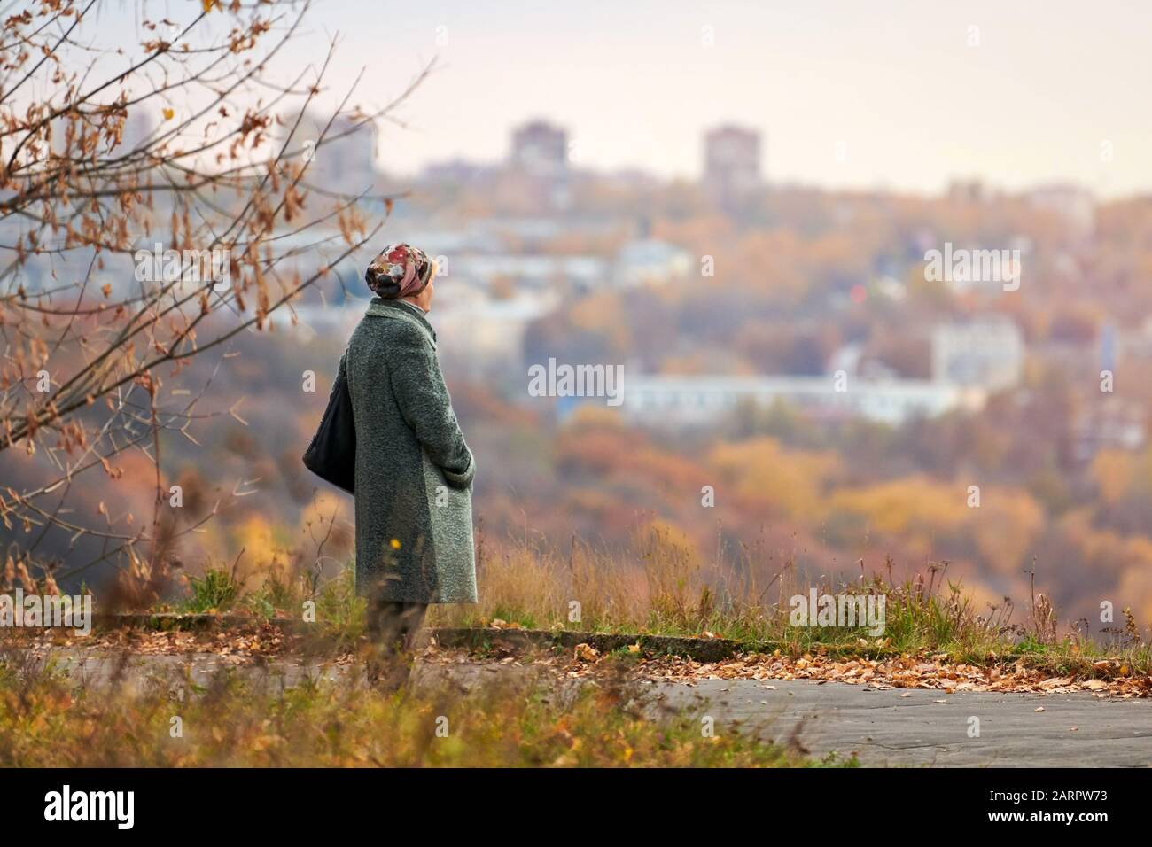 Vieille veuve marchant dans le parc de la ville d'automne. Femme solitaire regardant profondément la ville, l'auto-réflexion. Grand-mère rêvant de son concept familial. Banque D'Images