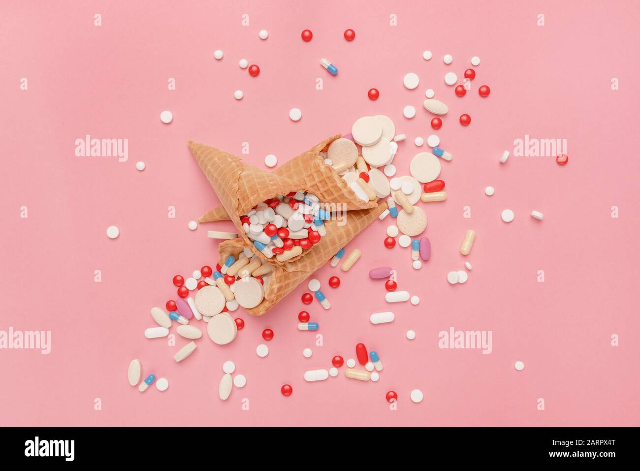 Comprimés de pilules et capsules dans les cônes de crème glacée, abus de drogues et concept de surutilisation, vue plate dessus de la couche. Banque D'Images