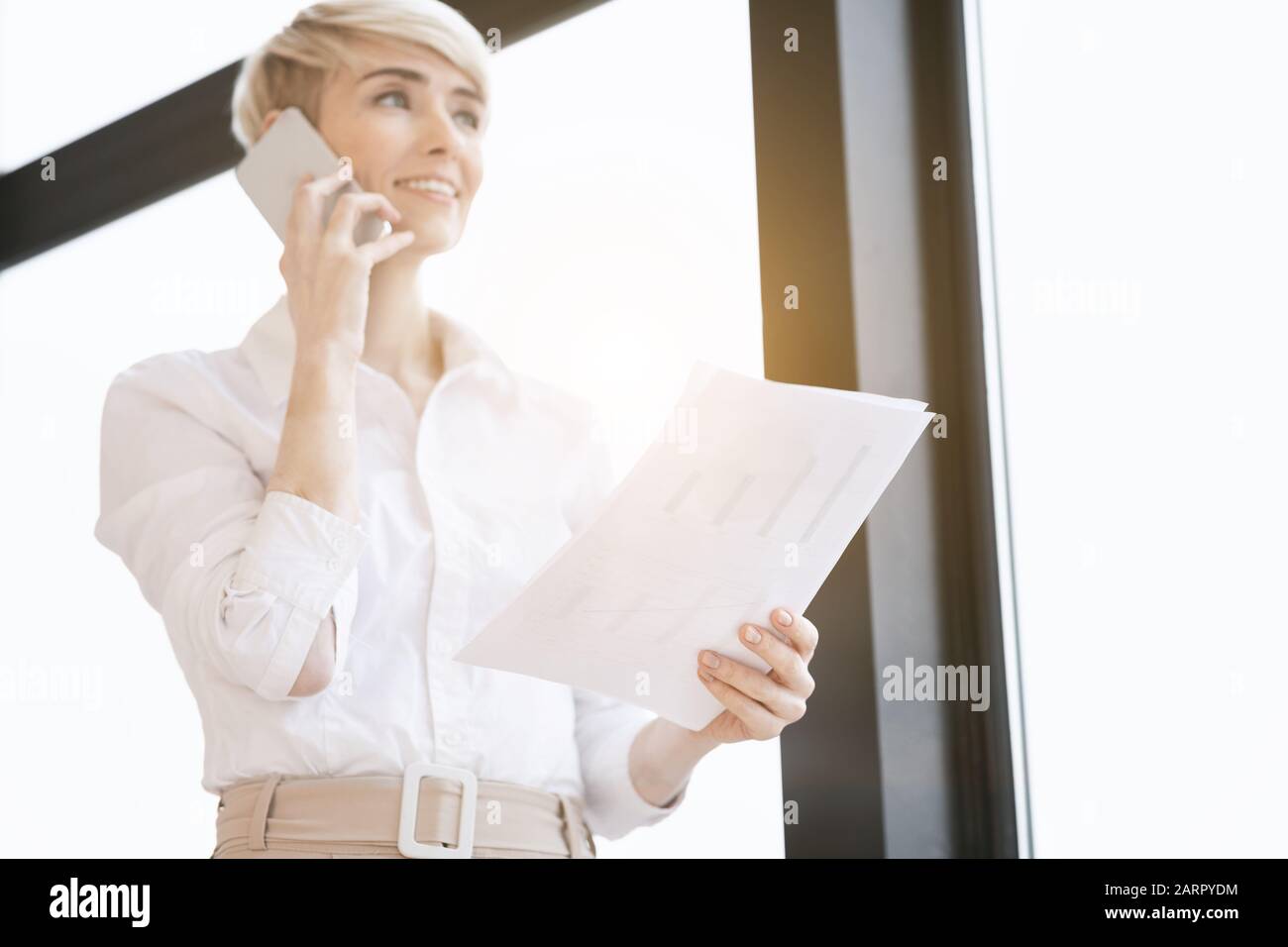 Lady Entrepreneur Parle Sur Téléphone Debout Près De La Fenêtre Au Bureau Banque D'Images