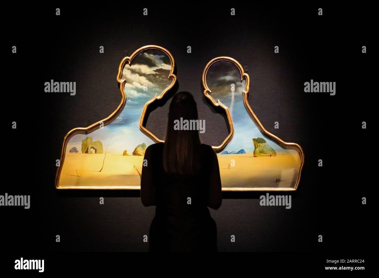 Bonhams, New Bond Street, Londres, Royaume-Uni 29 Jan 2020: - un membre du personnel voit Salvador Dal’, Couple aux ttes de plis nuages (1937) (est £7 à £10 m) à l'aperçu de Bonhams Impressionist et Modern Art Sale. Dal’ a créé Un Couple aux ttes de plis nuages (1937) alors qu’à Cadaqus pendant la guerre civile espagnole C au plus fort de sa période surréaliste (1929-1939). Les motifs surréalistes emblématiques interagissent avec la scène C rochers dispersés, un arbre défiguré, des figures humaines indistinctes, une girafe au feu et des nuages qui traversent les têtes des panneaux, ajoutent aux sous-courants de Freudien souvent incarnés dans Dal’ Banque D'Images