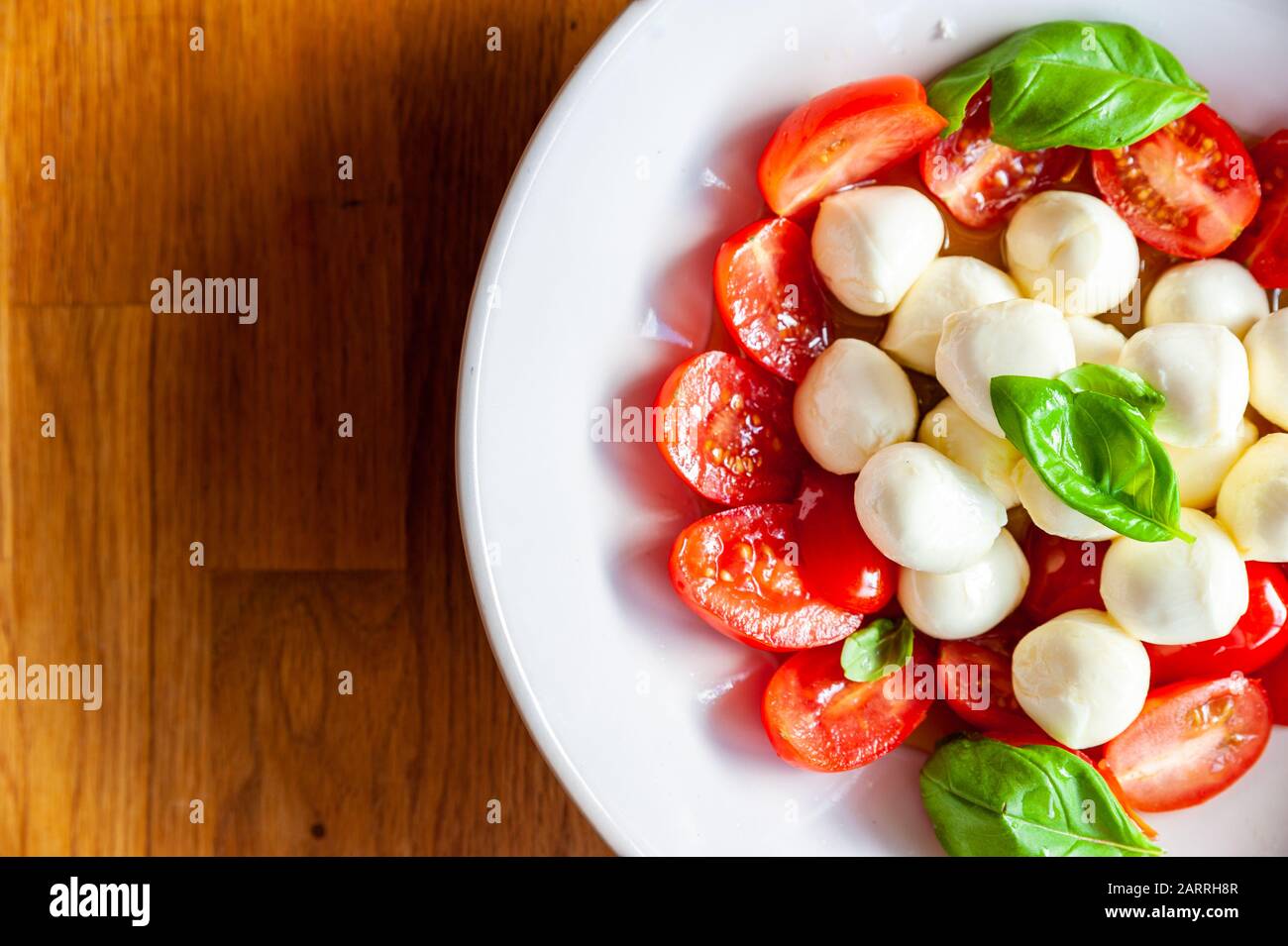 Dose détaillée d'un bol de salade de tomates avec mozzarella et basilic frais Banque D'Images