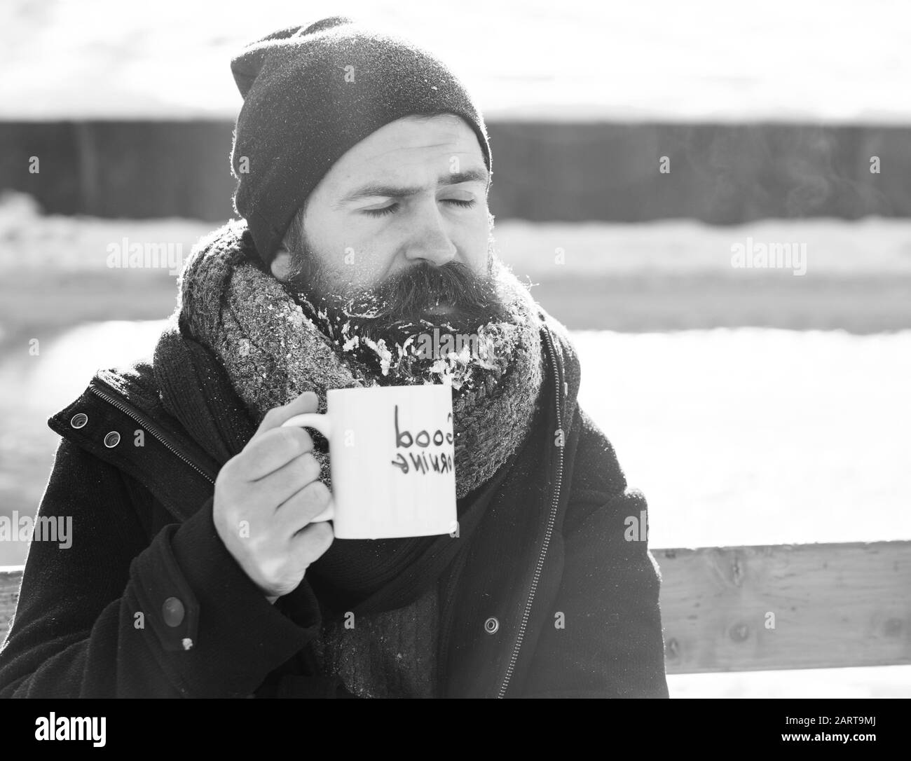L'homme fronce, barbu barbe et moustache hipster avec couverts de givre des boissons de tasse avec texte bonjour assis sur banc en bois on snowy winter journée en plein air sur l'arrière-plan naturel Banque D'Images L'homme fronce, barbu barbe et moustache hipster avec couverts de givre des boissons de tasse avec texte bonjour assis sur banc en bois on snowy winter journée en plein air sur l'arrière-plan naturel Banque D'Images