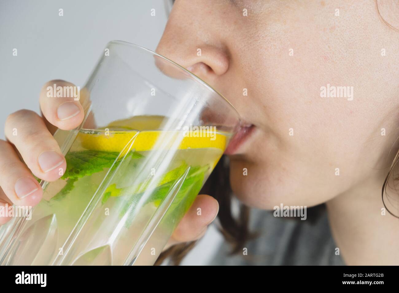 Verre de boisson au citron dans une main humaine. Cure de gueule de bois, eau tonique ou rafraîchissement de mojito Banque D'Images