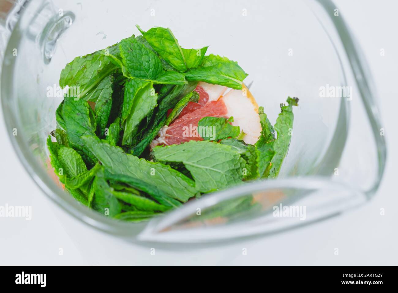 Feuilles de menthe poivrée fraîche et tranches de pamplemousse dans une vue rapprochée en verre. Préparation de l'eau tonique ou de la limonade, concept sain de boisson fraîche Banque D'Images