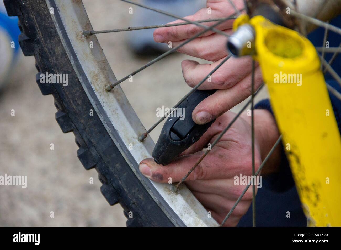 Portrait des mains d'une personne tenant une petite pompe à air pour faire sauter un pneu plat sur une roue d'un vélo de type VTT. Banque D'Images