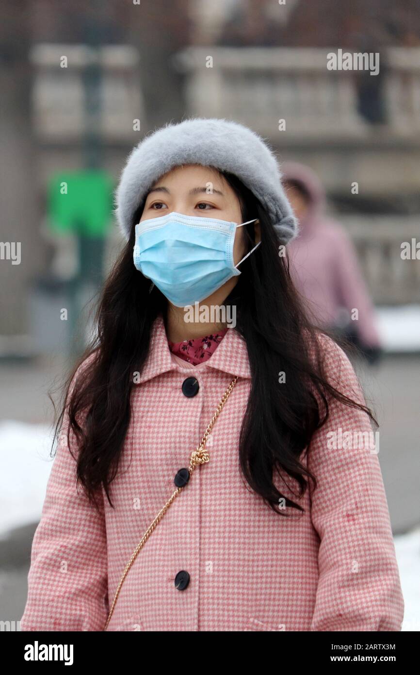 Protection contre le coronavirus, fille chinoise dans un masque médical protecteur debout sur une rue de ville d'hiver dans la foule, photo verticale Banque D'Images