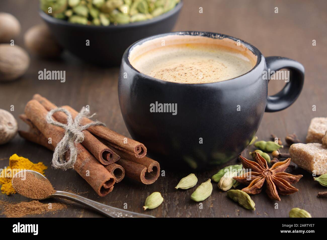 Tasse de café aux épices. Bâtons de cannelle, cardamome, épices, curcuma et anis sur table en bois. Banque D'Images