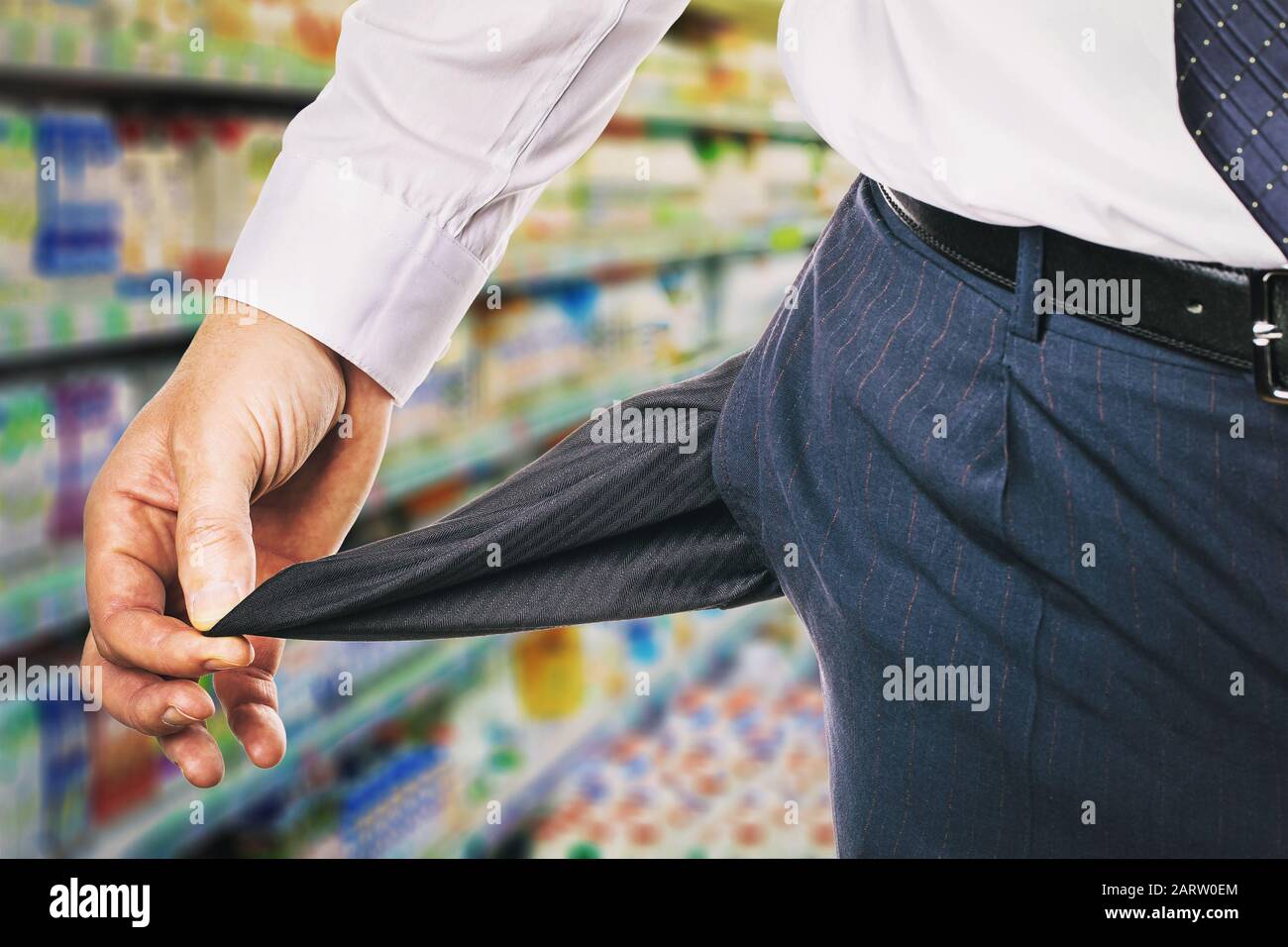 L'homme montre une poche vide sur l'arrière-plan du magasin. Le concept du manque d'argent pour les achats Banque D'Images