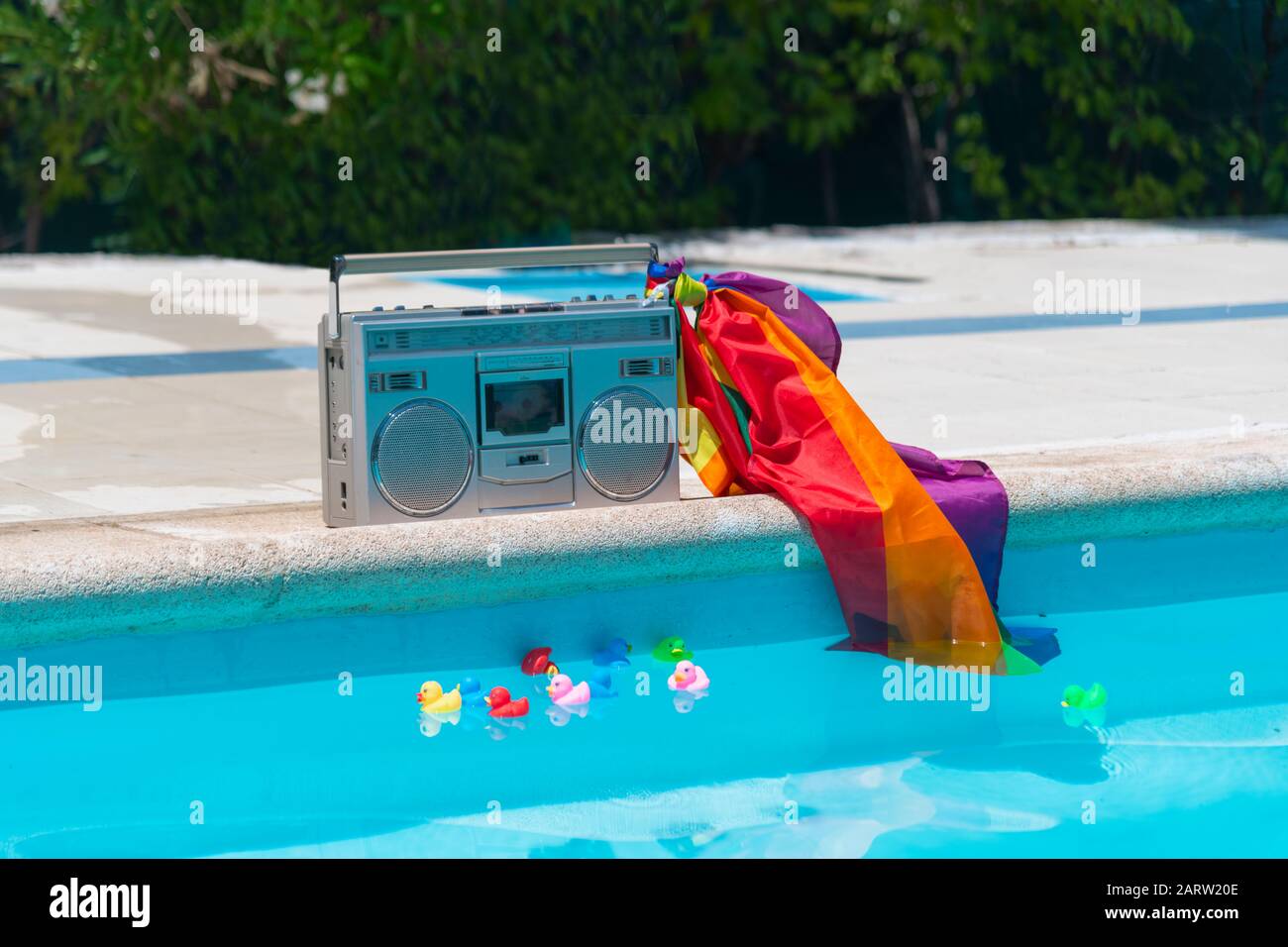 Radio cassette avec drapeau de fierté gay au bord de la piscine avec  différents canards en caoutchouc de couleur nageant à la piscine sur un  fond hors du foyer. Gay et plongeur