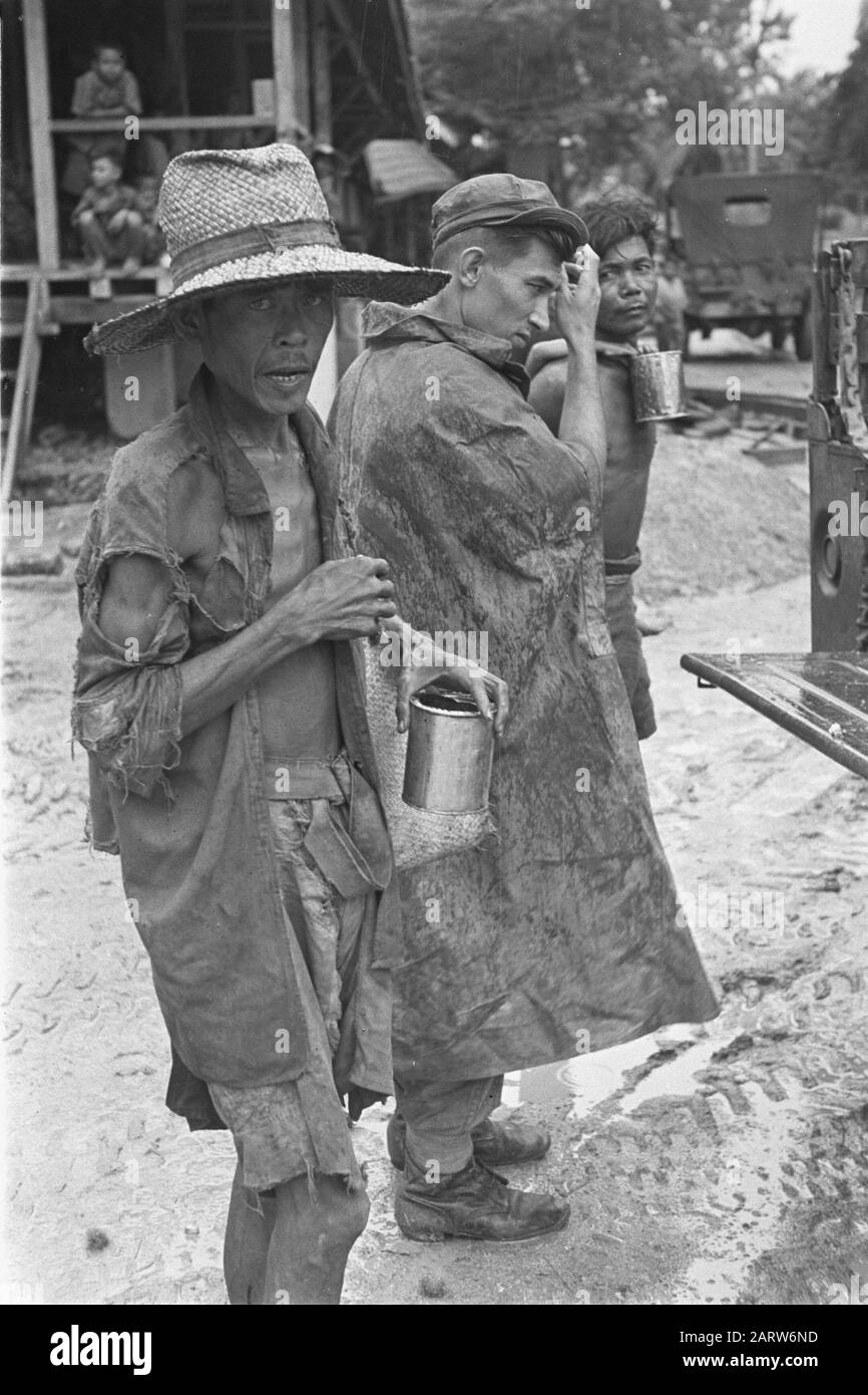 Photo Retarage Palembangs Fortement skinneyed l'homme indonésien. Au milieu du soldat néerlandais, homme avec enfant et regard. Jeeps Date : Janvier 1947 Lieu : Indonésie, Antilles Orientales Néerlandaises, Palembangs, Sumatra Banque D'Images