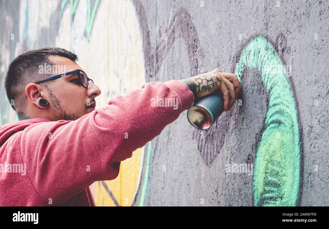 La peinture d'artiste de graffitis de rue avec un spray de couleur peut murale graffitis sur le mur dans la ville - urbain et moderne concept de style de vie d'art de rue Banque D'Images