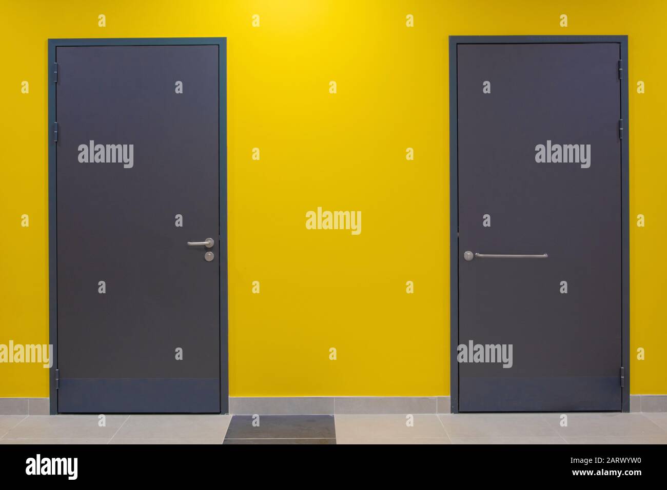 Deux portes grises fermées sur un mur jaune Banque D'Images