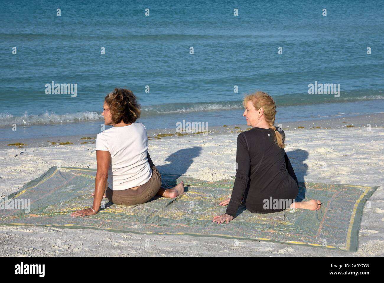 Deux Belles femmes d'âge mûr faisant du yoga au lever du soleil sur la plage Banque D'Images