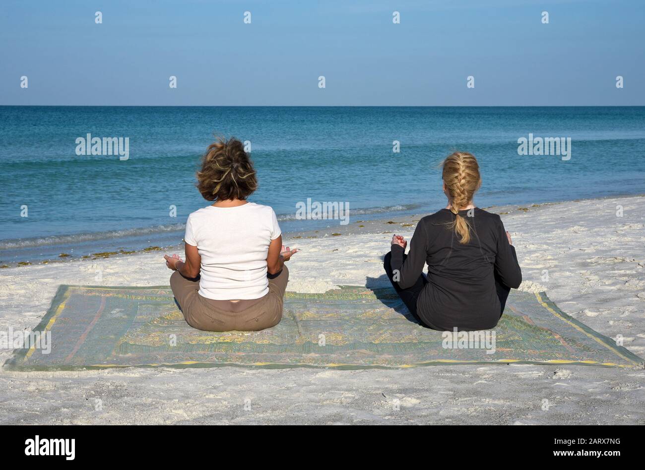 Deux Belles femmes d'âge mûr faisant du yoga au lever du soleil sur la plage Banque D'Images