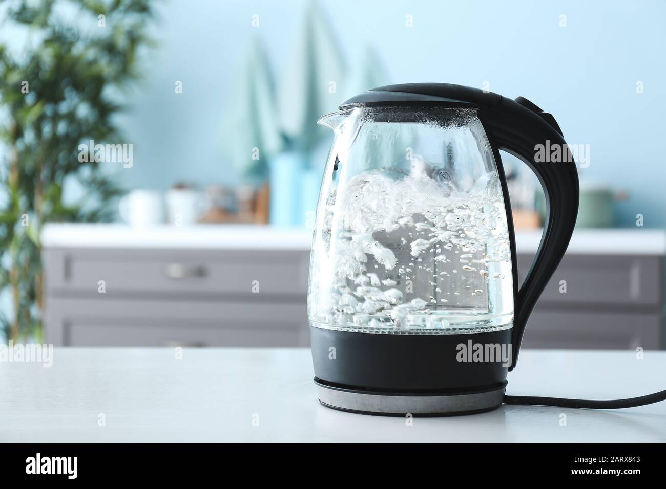bouilloire électrique transparente avec eau bouillante sur la table dans la cuisine Banque D'Images