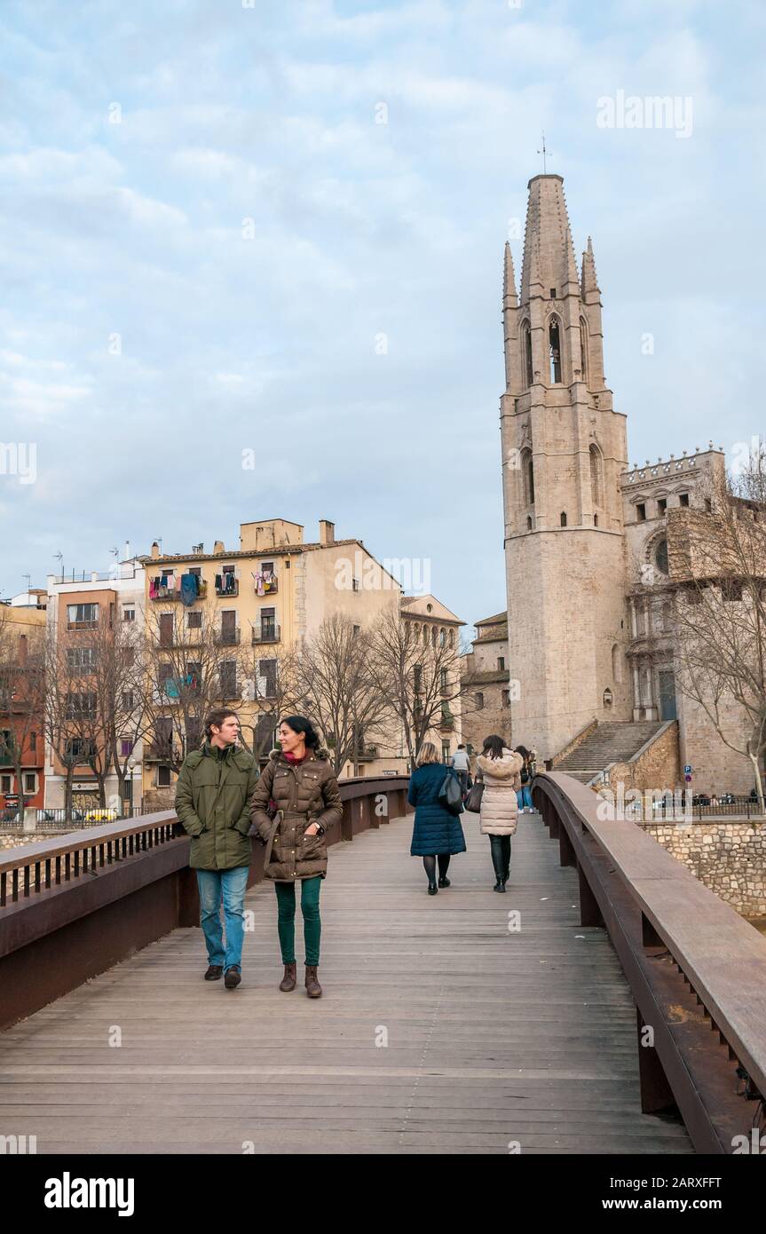 Les gens marchant sur un pont au-dessus de la rivière Onyar, les maisons sur la rivière Onyar avec l'église Sant Felix sur le fond, Gérone, Catalogne, Espagne Banque D'Images