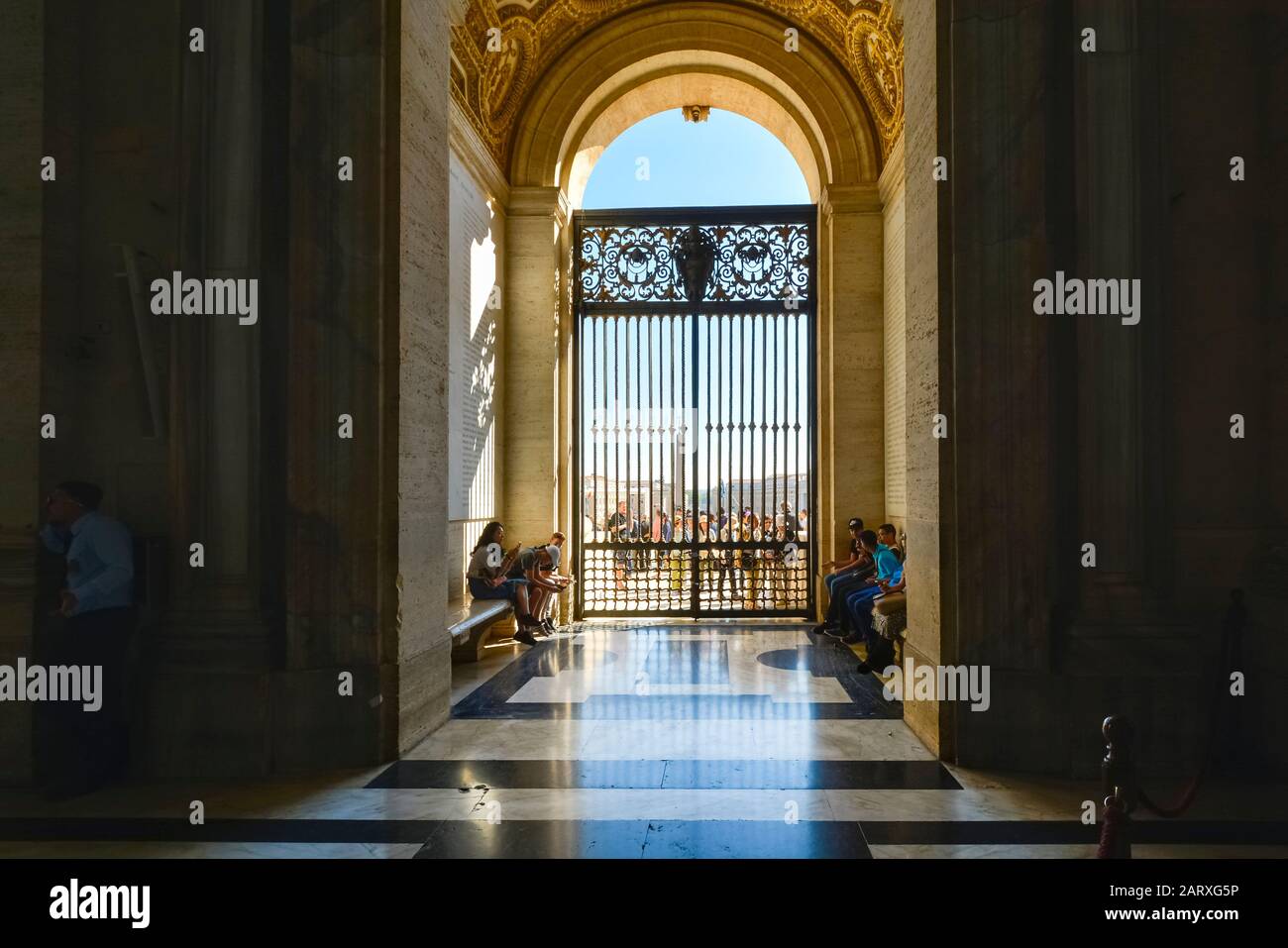 La lumière du soleil brille sur les touristes alors qu'ils attendent devant les portes de la basilique de la cathédrale Saint-Pierre dans la Cité du Vatican. Banque D'Images