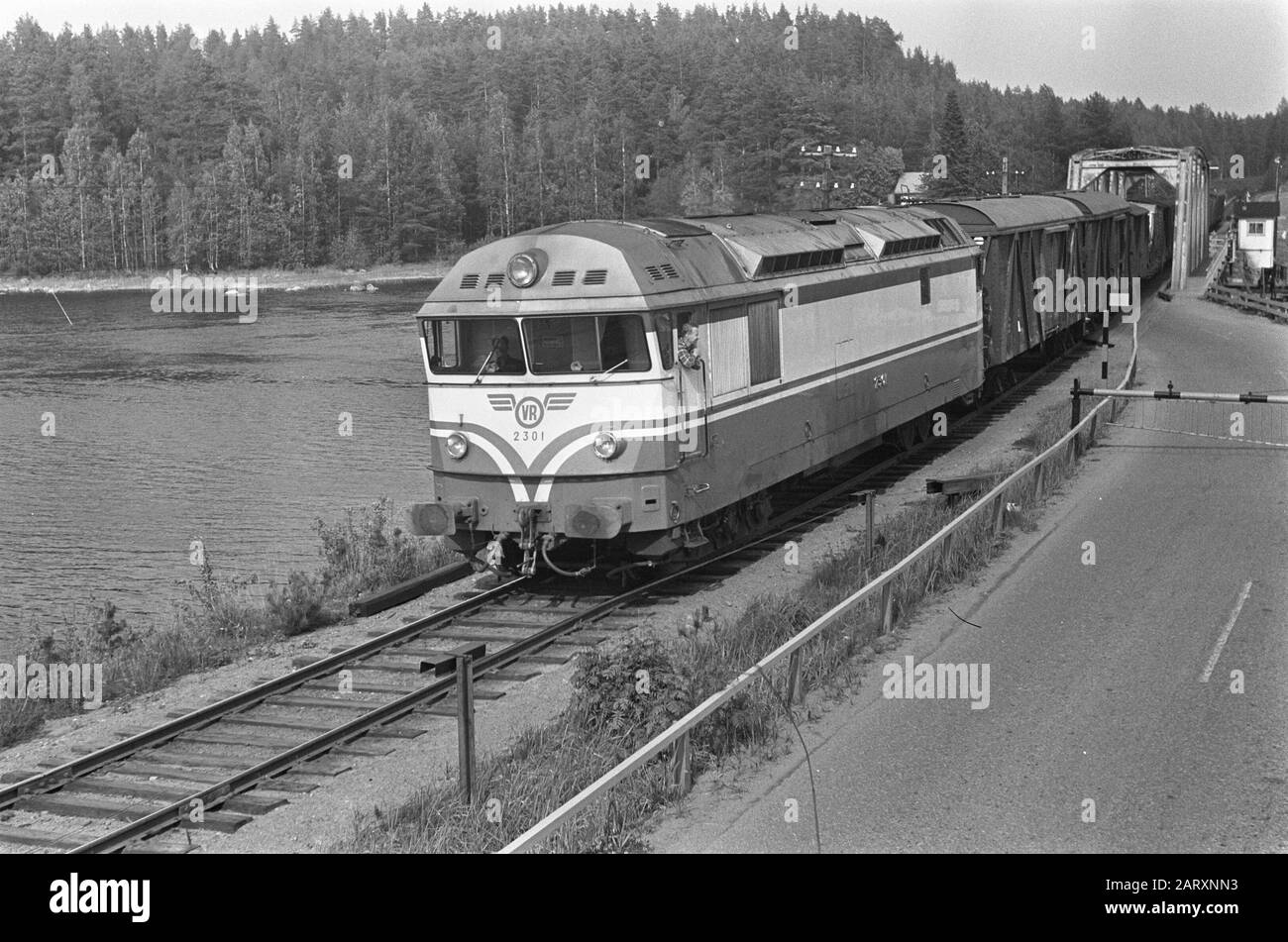 Un train de marchandises transporté par une locomotive diesel VR classe R-13 (n° 2301) sur un pont routier-ferroviaire non identifié en Finlande en juillet 1967. Annotation: Description en log: 2 train finlandais, 1 fille en forêt au lac Date: 5 juillet 1967 lieu: Finlande mots clés: Locomotives, voyage, chemins de fer, trains, moyens de transport Banque D'Images