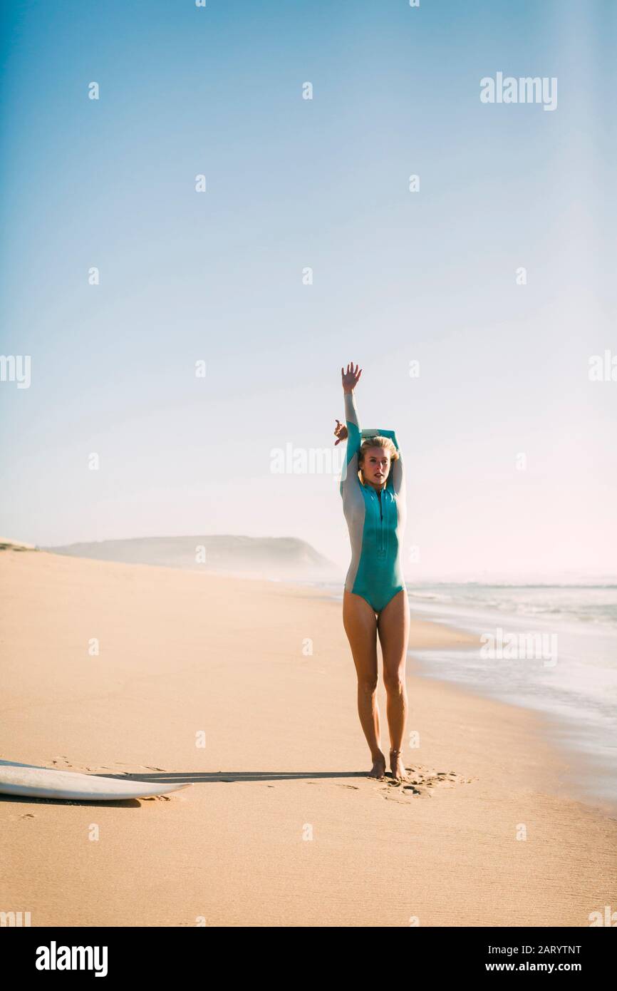 Femme portant une combinaison qui s'étend sur la plage Banque D'Images