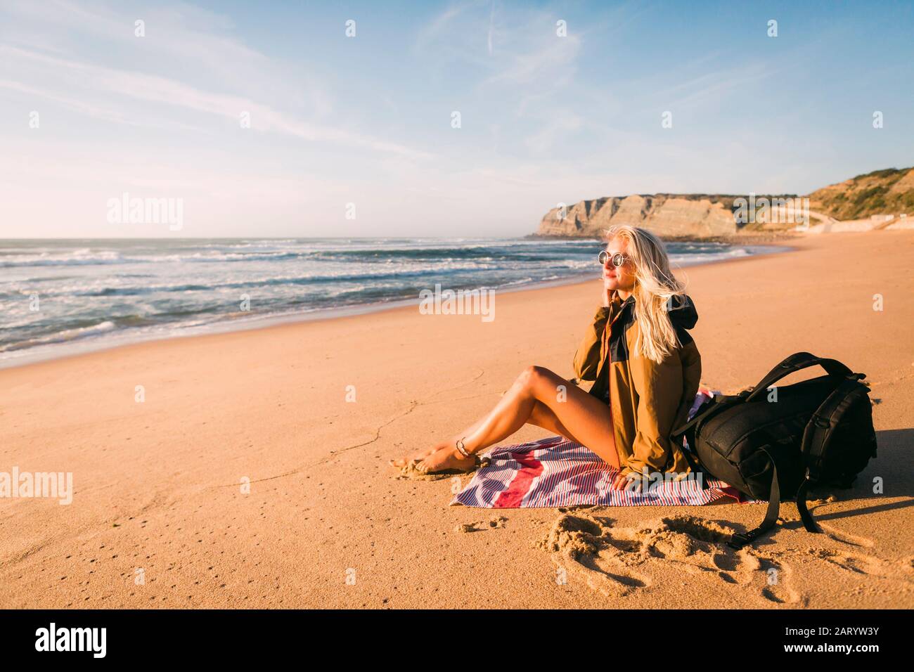 Femme assise sur towel on beach Banque D'Images