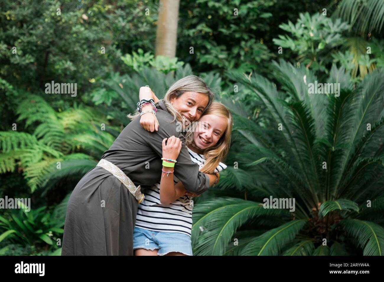 Mère et fille souriant et embrassant par le Bush Banque D'Images