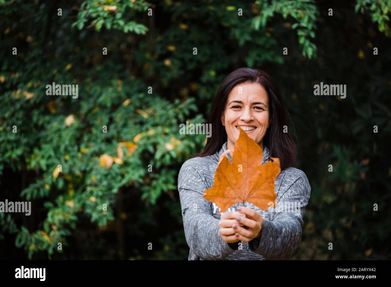 Smiling woman holding autumn leaf Banque D'Images