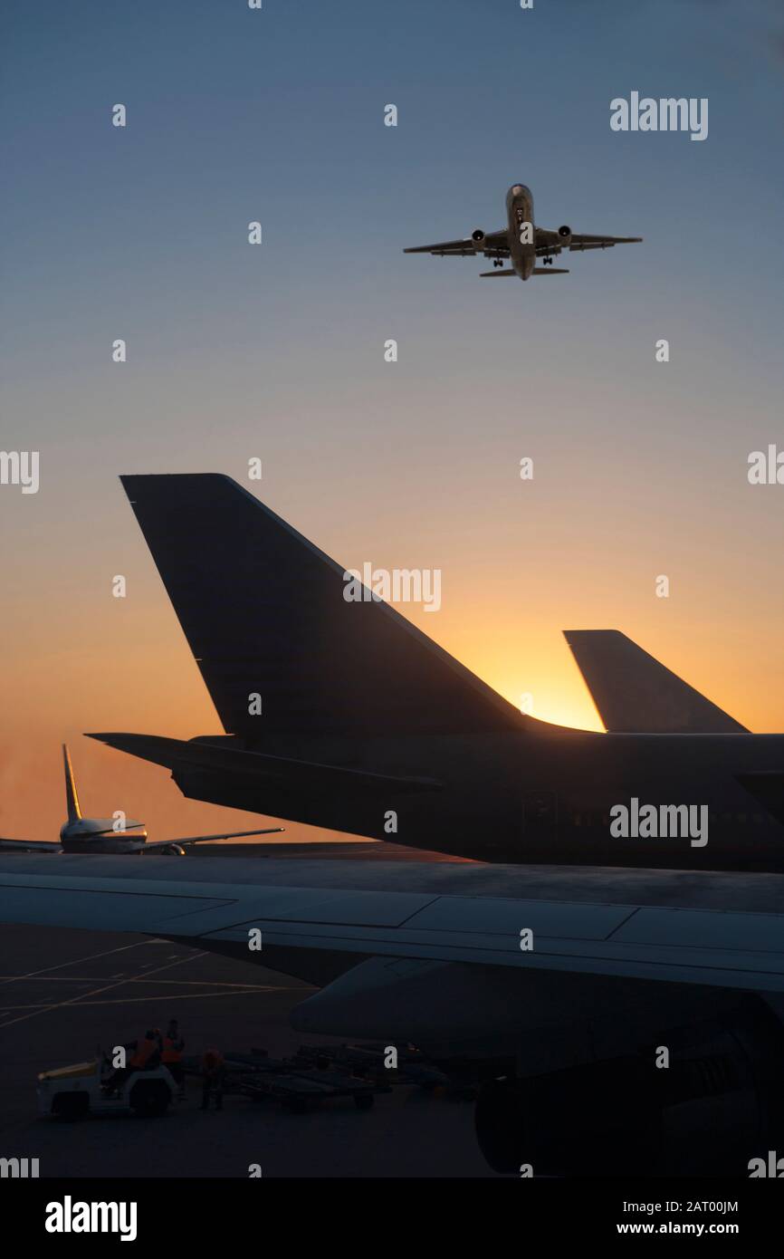 Avion survolant l'avion sur la piste au coucher du soleil Banque D'Images