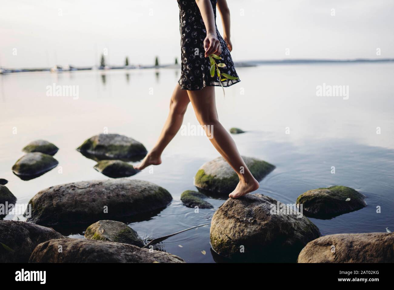 Femme pieds nus marchant sur des rochers en mer Banque D'Images