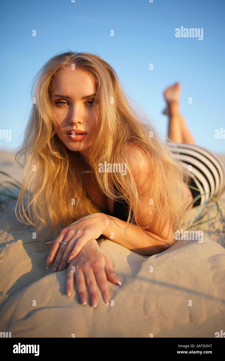 Femme blonde allongée sur le sable Banque D'Images