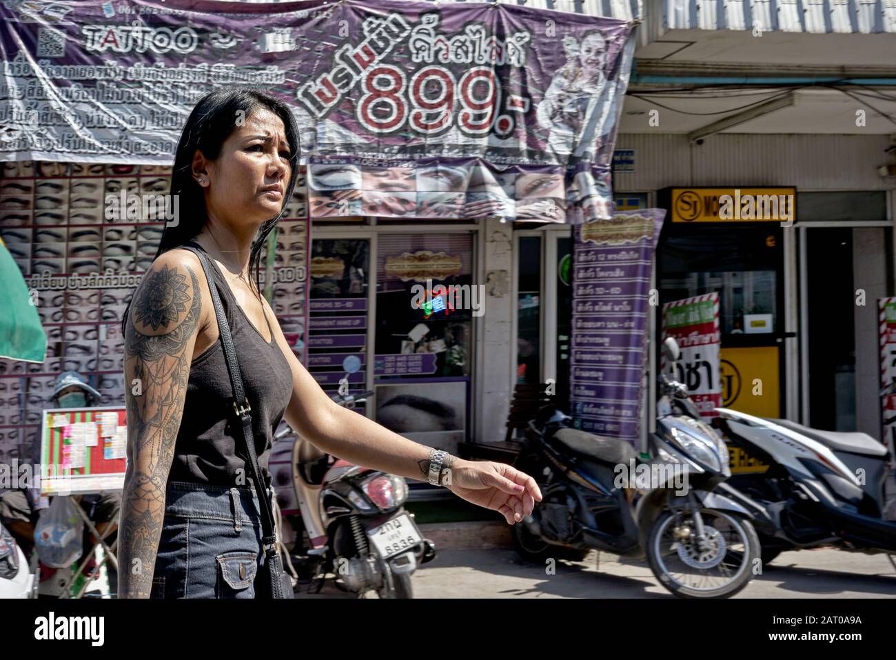 Femme avec bras tatoué marchant devant un salon de tatouage, Thaïlande S. E. Asia Banque D'Images
