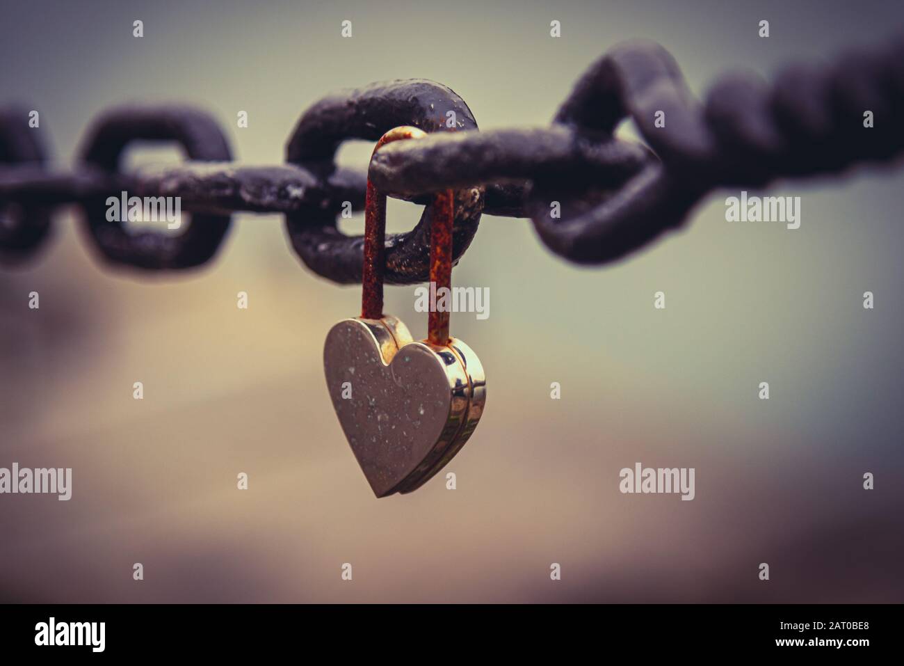 Un romantique et fermée en forme de coeur rouillé suspendu à un cadenas à côté d'une chaîne avec la rivière paysage flou en arrière-plan. Concept de longue durée Banque D'Images