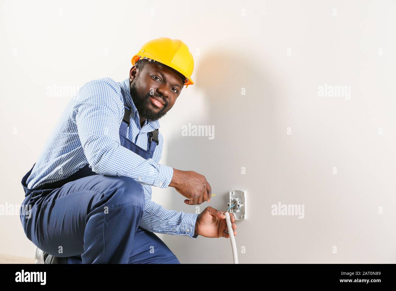 Électricien afro-américain remplaçant la prise dans la chambre Banque D'Images