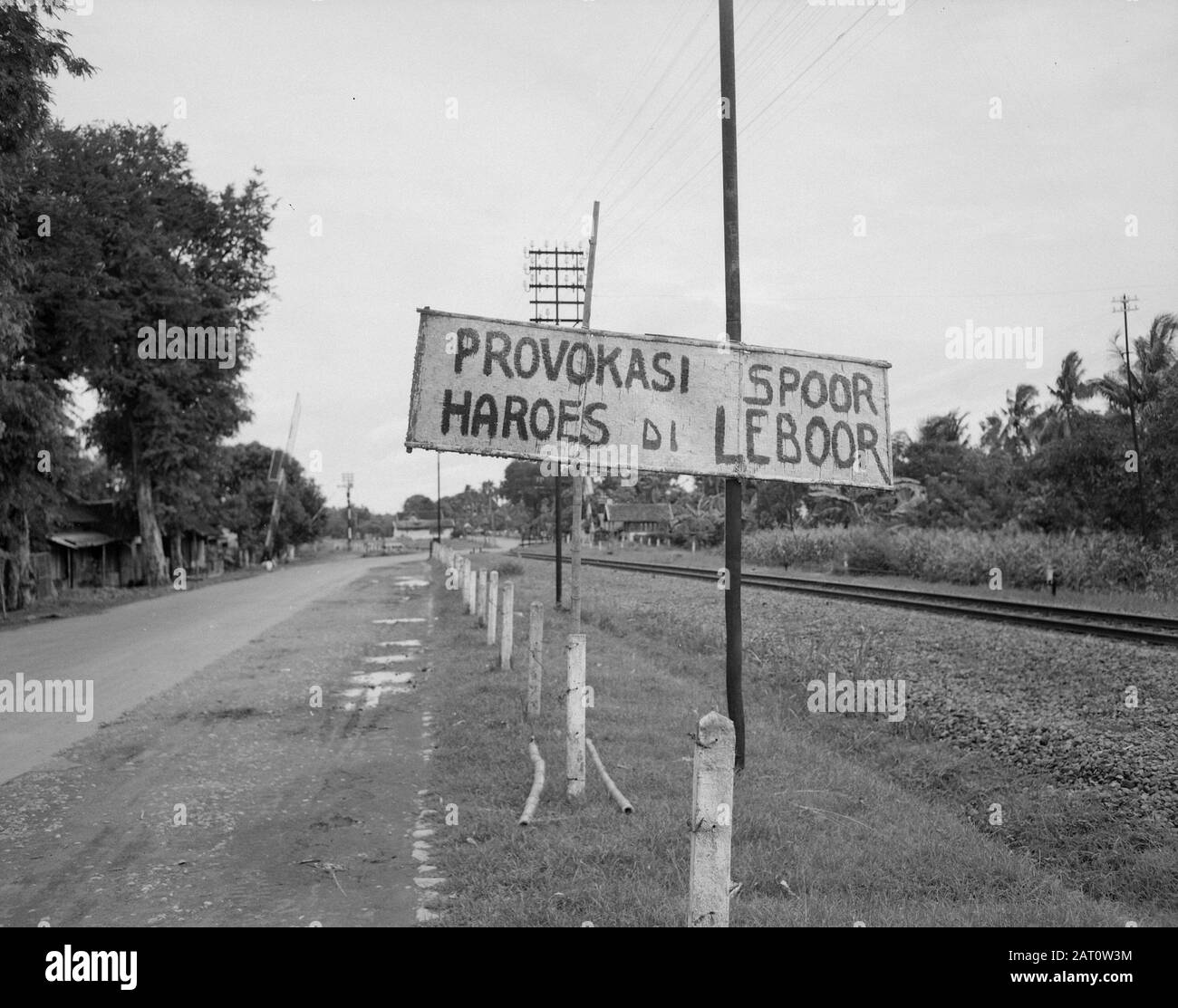 Service d'information de l'armée Surabaya UNE longue route avec chemin de fer. Sur un signe, le texte "Provokasi Spoor" hoes di leboor] Annotation: Par rail est probablement signifie général Spoor. Provocations Traduites De Rail. Devrait? Date : Février 1947 Lieu : Indonésie, Antilles Néerlandaises De L'Est, Surabaya Banque D'Images