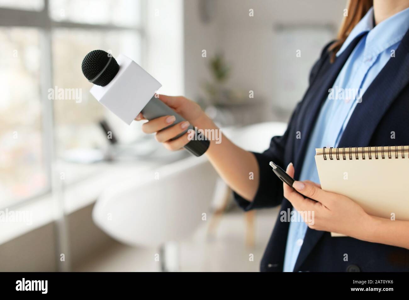 Journaliste féminine avec microphone ayant une entrevue au bureau Banque D'Images