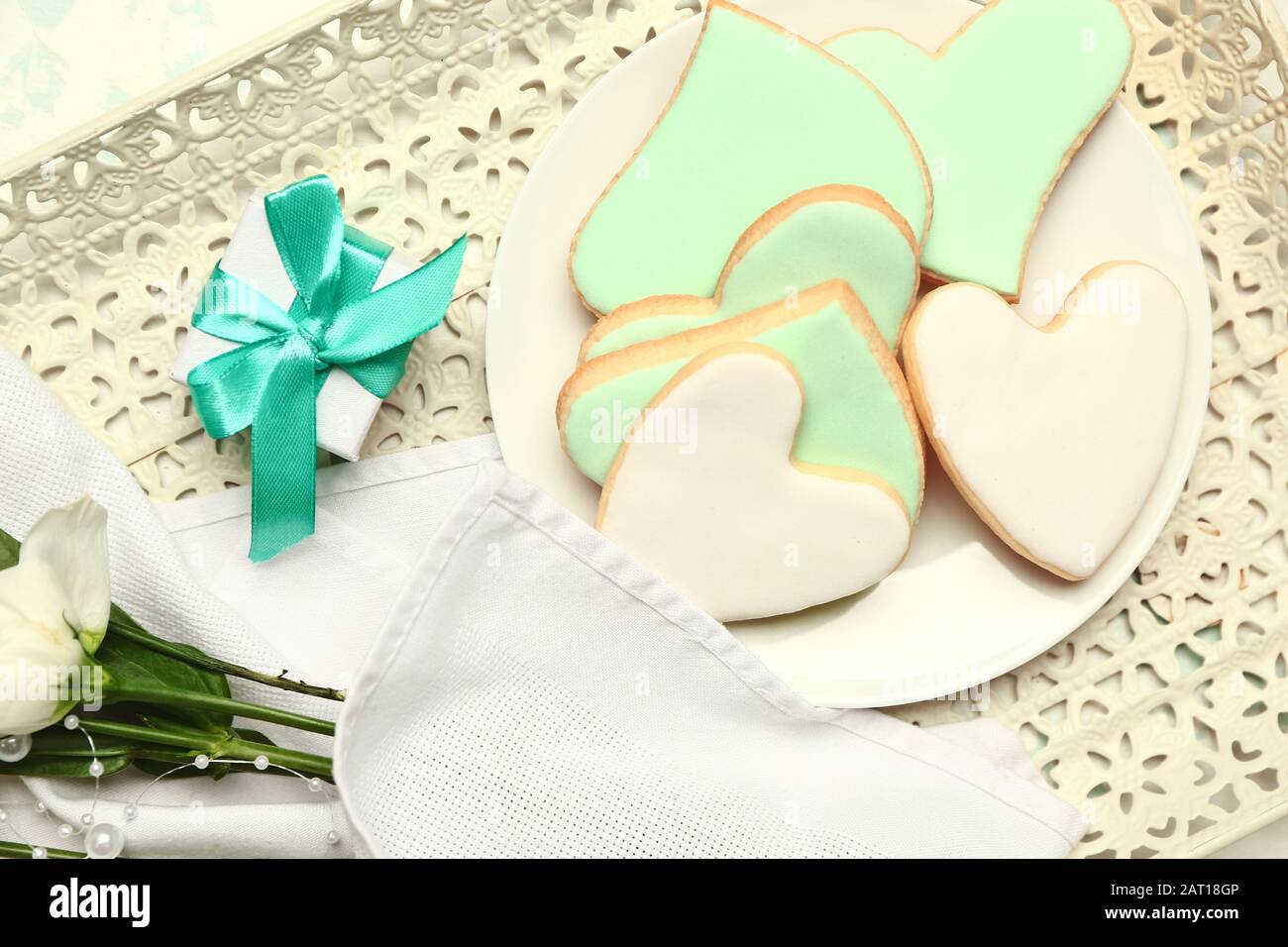 Plaque avec délicieux cookies en forme de coeur, cadeau et fleurs sur le plateau de la fête de la Saint Valentin Banque D'Images