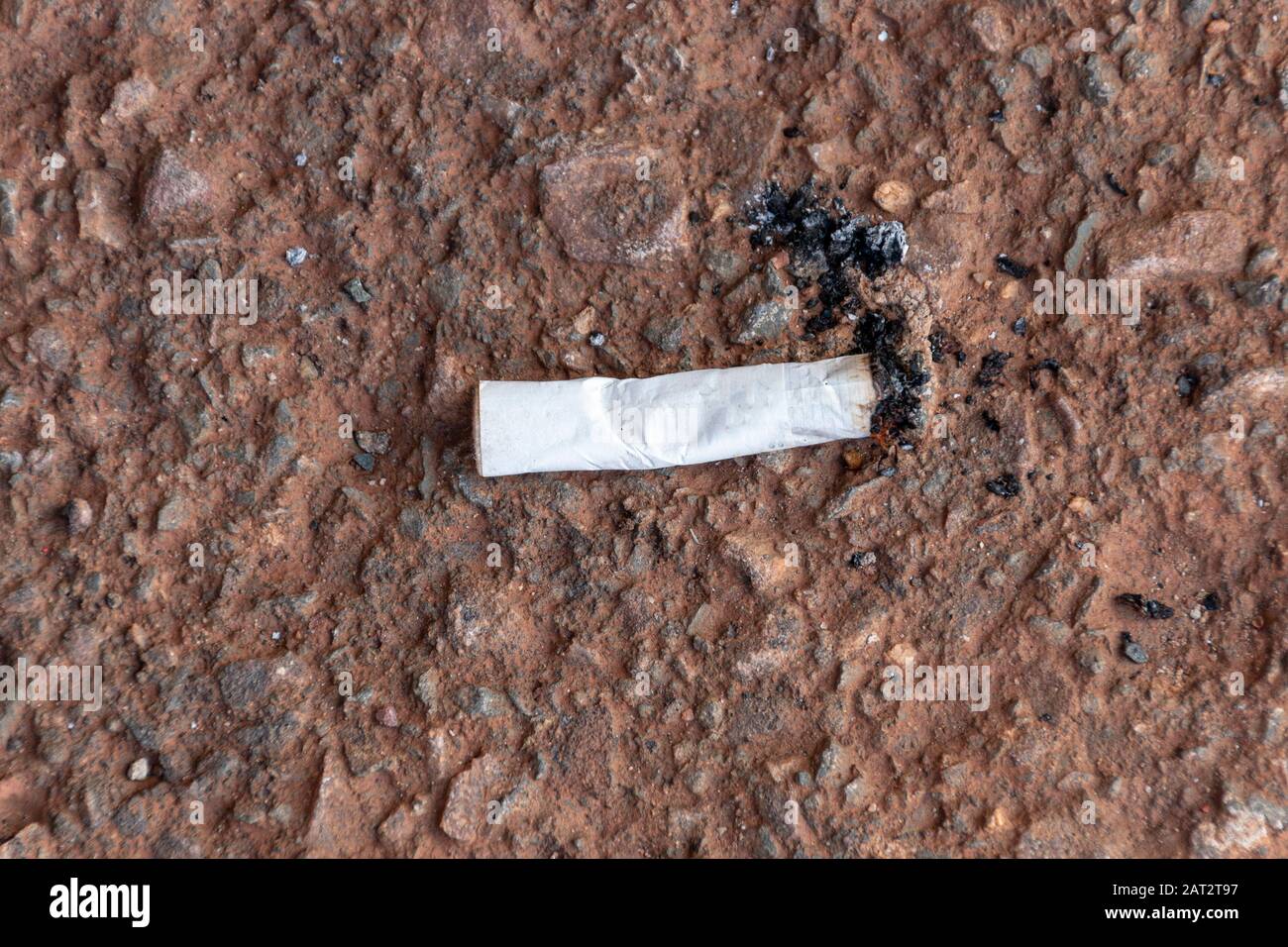 Vue rapprochée d'un bourgeon de cigarette qui a été mis sur le goudronnet rouge Banque D'Images