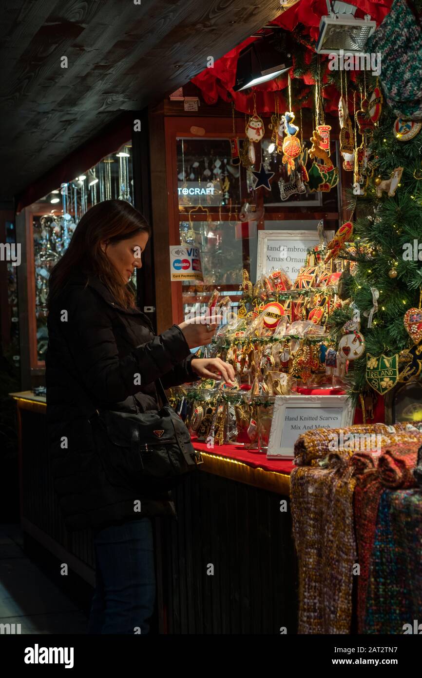 Londres / Royaume-Uni - 24 novembre 2019 : femme achetant des souvenirs dans un stand sur le marché de Noël sur la Trafalgar's Square à Londres Banque D'Images