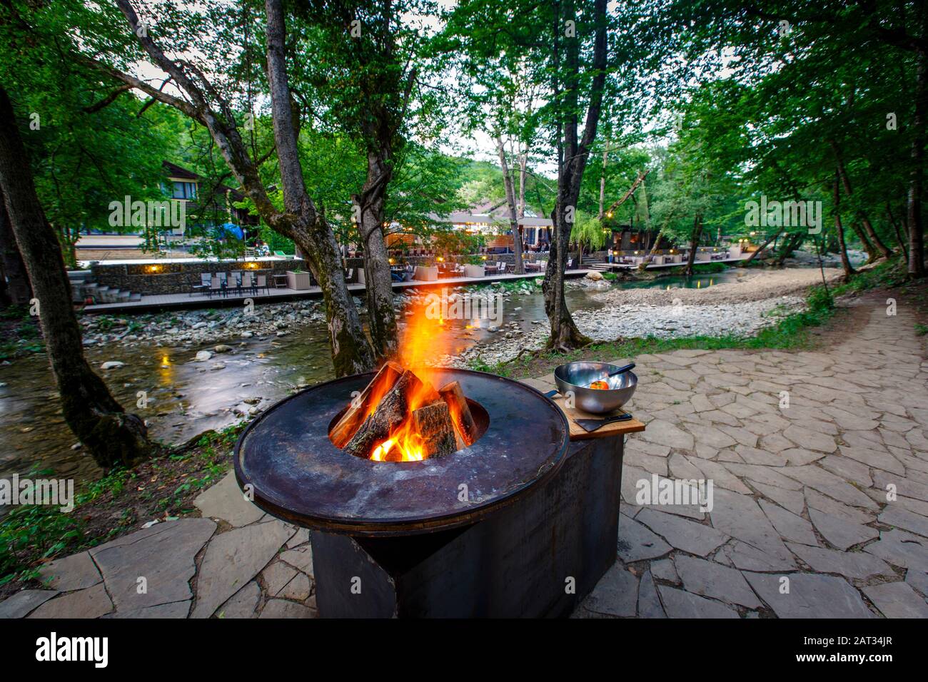 Barbecue avec un feu brûlant sur la rive de la montagne en soirée. À côté des légumes du gril préparés pour la friture : poivrons, tomates, mu Banque D'Images