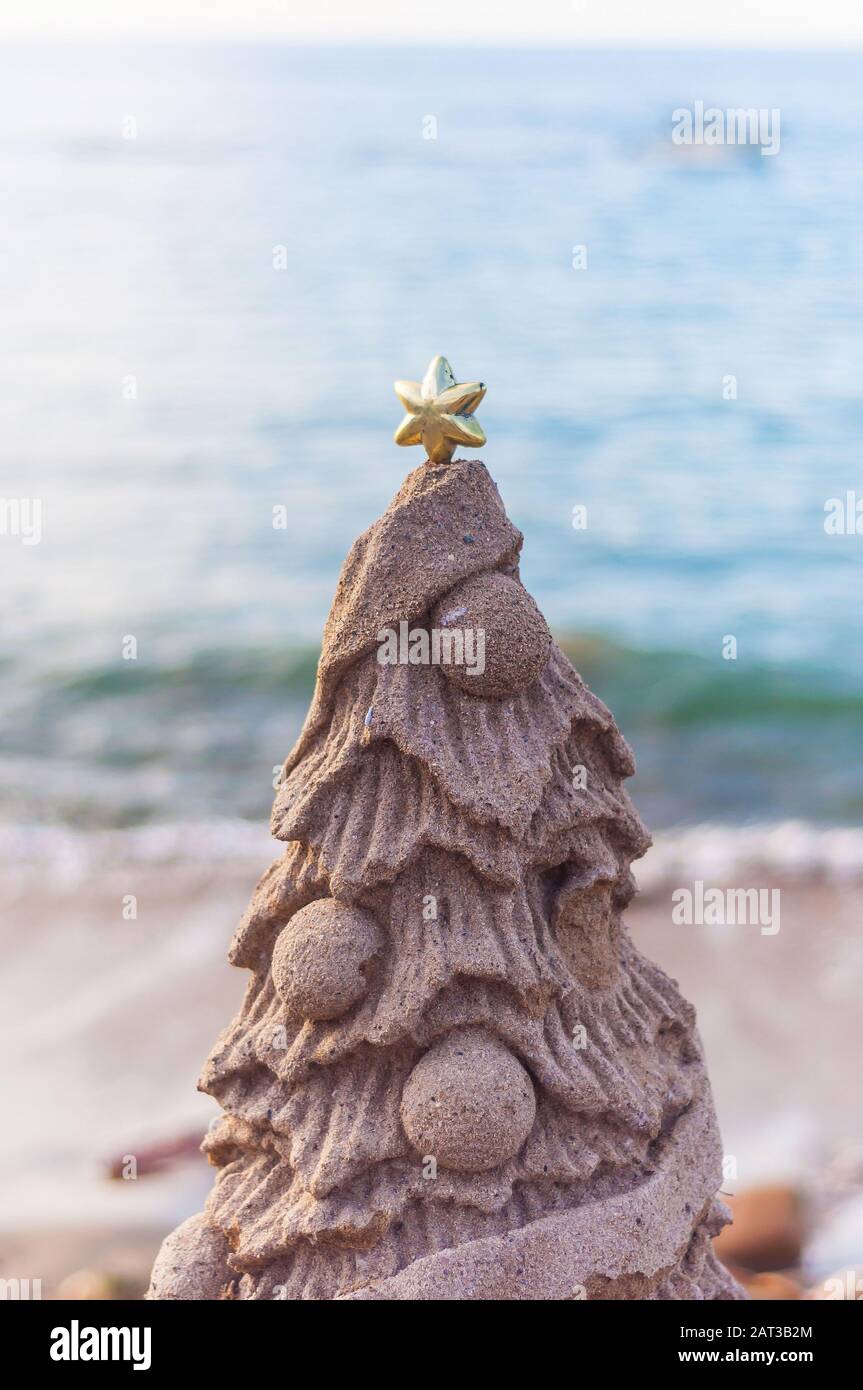 Gros plan vertical d'un arbre de Noël en forme de sable sur la plage Banque D'Images