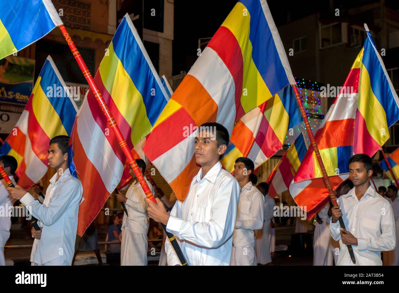 Les porteurs de drapeau bouddhiste marchent solennellement le long d'une rue à Kandy au Sri Lanka pendant le Bouddhiste Esala Perahera (grande procession). Banque D'Images