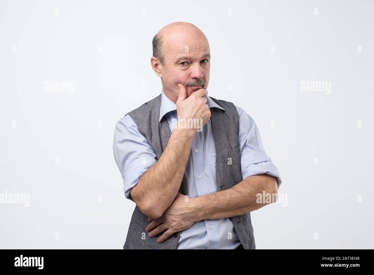 Homme hispanique senior en maillot et maillot de corps pensant et regardant pensif avec le visage réfléchi. Concept d'expression faciale isolé sur fond blanc. Banque D'Images