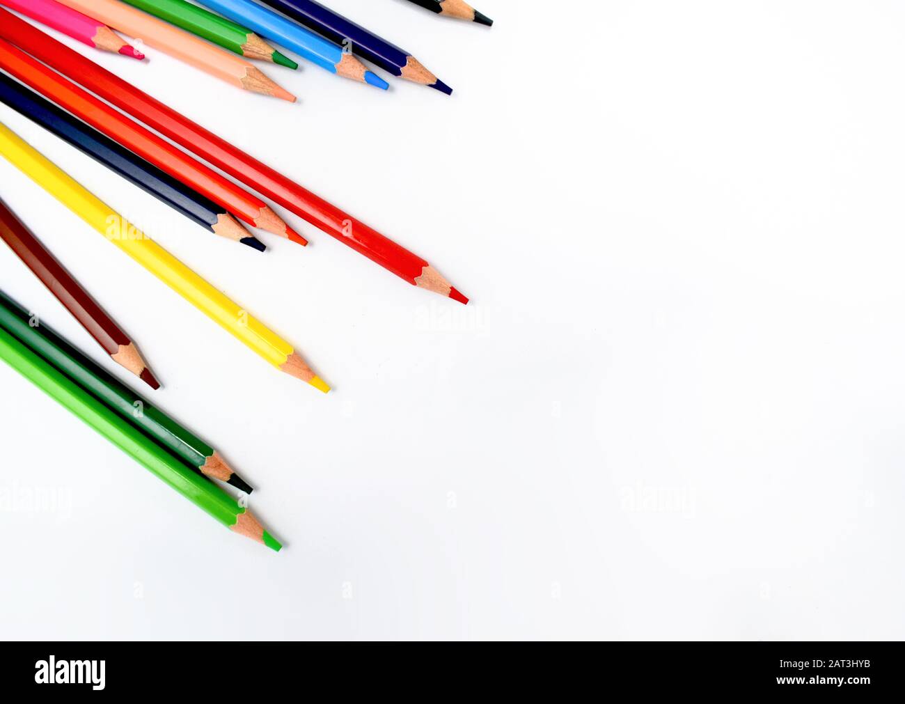 des crayons de cire de différentes couleurs sont dispersés aléatoirement sur un fond blanc brillant Banque D'Images