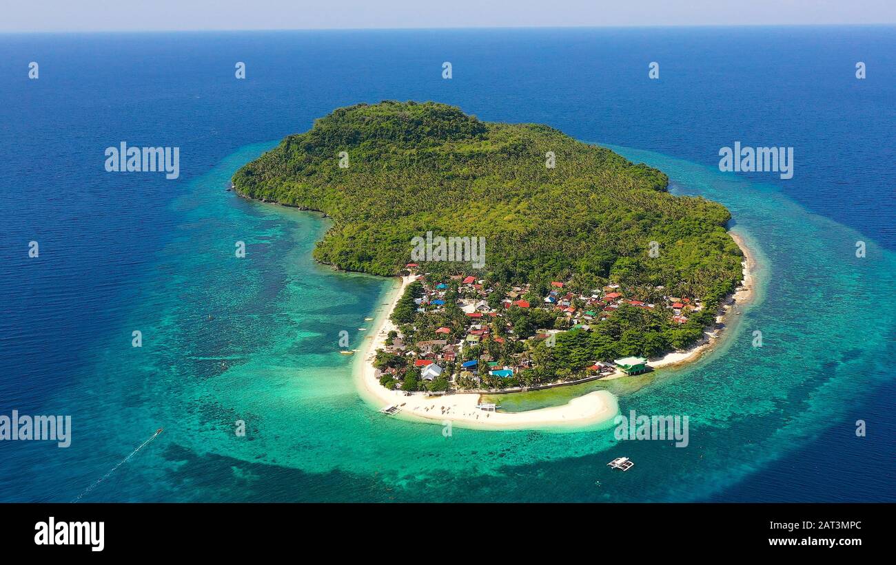Himokilan Island, l'île de Leyte, aux Philippines. Île tropicale avec un village et d'une plage de sable blanc. L'eau turquoise et des récifs coralliens autour de l'île. Maison de vacances d'été. Banque D'Images