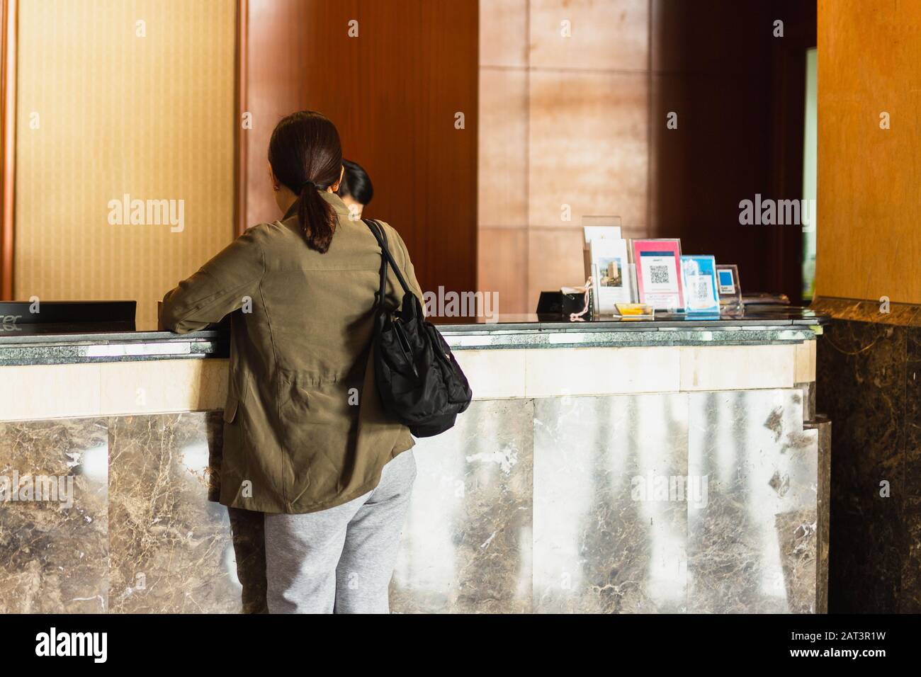 Femme demandant des informations à la réception de l'hôtel Banque D'Images