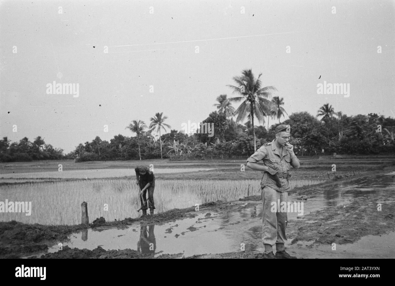 Dans la dessa, un militaire a édité une route avec un pioche. Une autre cigarette fume Date: 19 décembre 1947 lieu: Indonésie, Pays-Bas Indes orientales Banque D'Images